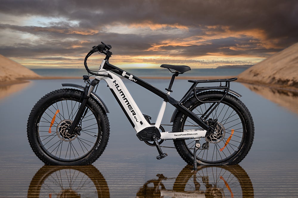 Side View of the AWD Electric Bike Parked on the Beach in a Puddle of Water with a Colorful Sunset View in the Background