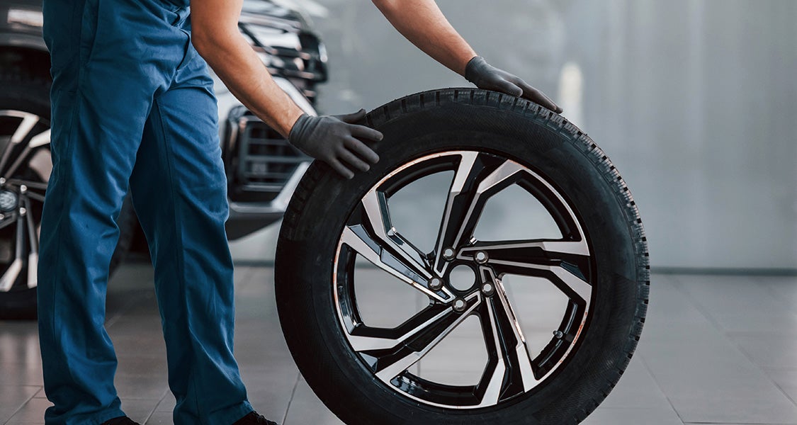 Mechanic inspecting a vehicle tire and wheel assembly in an automotive service center